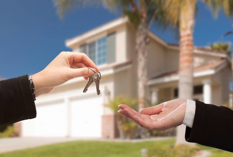 Handing over the new house keys with home in the background