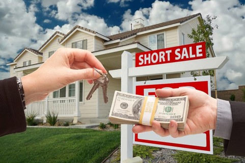 Handing over cash for house keys and short sale real estate sign in front of home