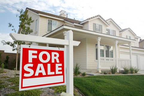 For sale real estate sign in front of beautiful new home