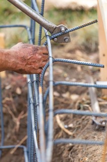 Worker using tools to bend steel rebar at construction site