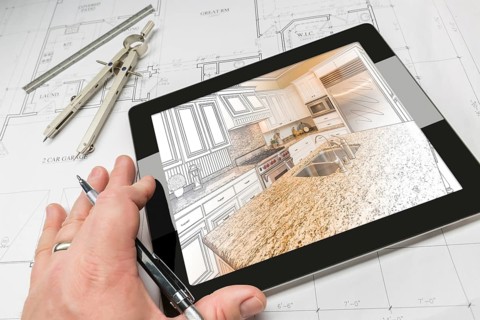 Hand of architect on computer tablet showing custom kitchen illustration photo combination over house plans
