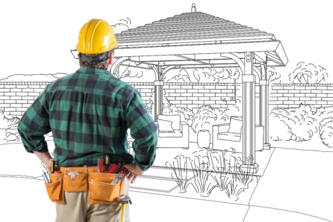 Contractor standing looking at patio pergola design drawing