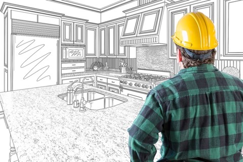 Male contractor with hard hat looking at custom kitchen drawing on white