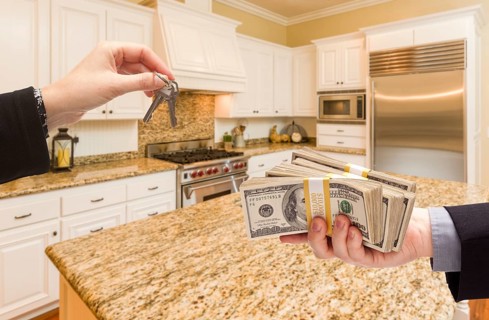 Handing over keys for cash in beautiful custom kitchen interior