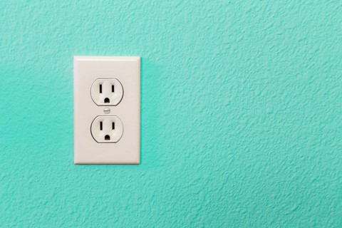 Electrical sockets in colorful bright teal wall of house