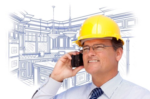 Contractor in hardhat on cell phone over custom kitchen drawing on white