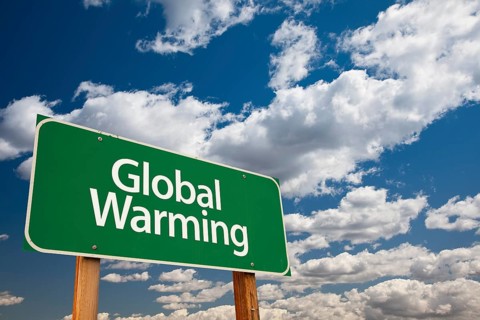 Global warming green road sign over dramatic clouds and sky