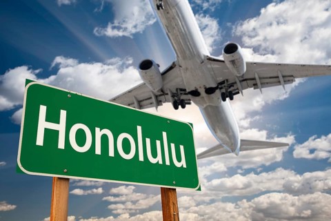 Honolulu green road sign and airplane above with dramatic blue sky and clouds