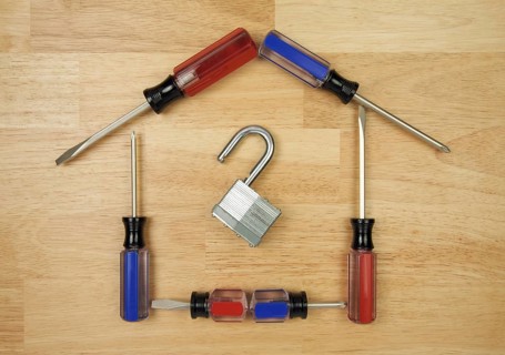 House shaped by screwdrivers and lock on a wood background