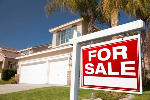 For sale real estate sign in front of house