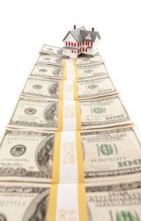 Small house on row of hundred dollar bill stacks isolated on a white background