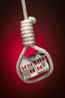 House tied up and hanging in hangman's noose on red spot lit background