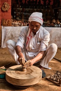 Indian potter at work: throwing the potter's wheel and shaping ceramic vessel and clay ware: pot