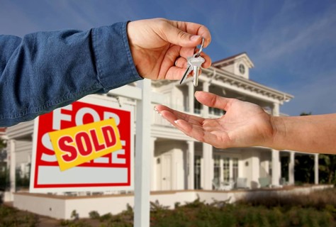 Handing over the house keys in front of a beautiful new home