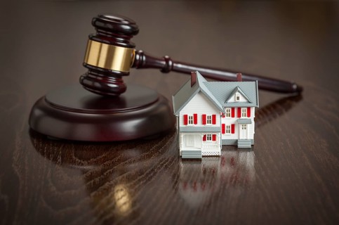 Gavel and small model house on wooden table