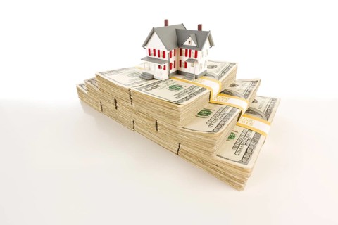 Stacks of one hundred dollar bills with small house on slight gradation