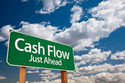Cash flow green road sign over dramatic clouds and sky