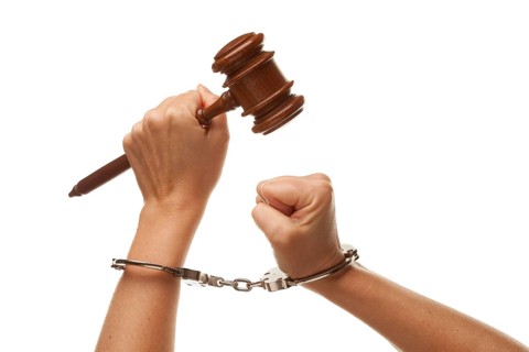 Handcuffed woman holding wooden gavel in her fist isolated on a white background