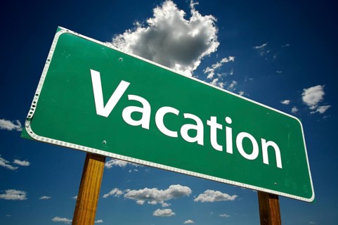 Vacation green road sign over dramatic blue sky and clouds with clipping path