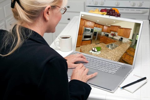 Woman in kitchen using laptop to research home improvement ideas. screen can be easily used for your own message or picture. picture on screen is my copyright as well