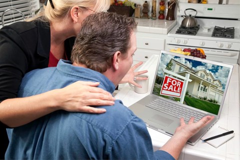 Couple in kitchen using laptop to research real estate. screen can be easily used for your own message or picture. picture on screen is my copyright as well