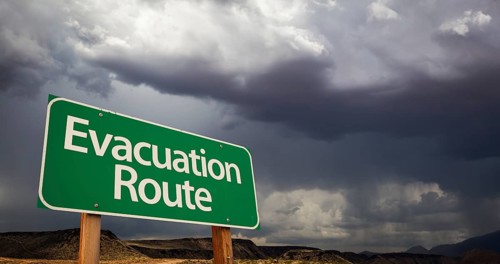 Evacuation route green road sign with dramatic clouds and rain