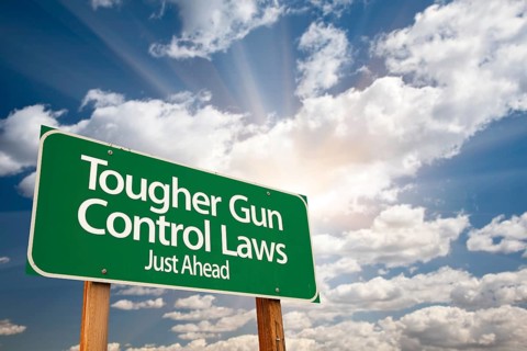 Tougher gun control laws green road sign with dramatic clouds and sky