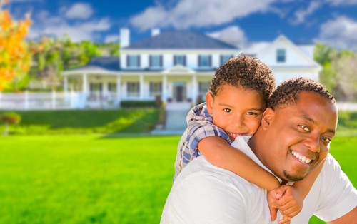 Happy playful african american father and mixed-race son in front of house