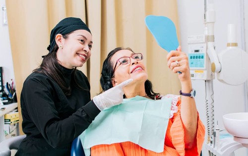 Satisfied female client in dental clinic looking at mirror