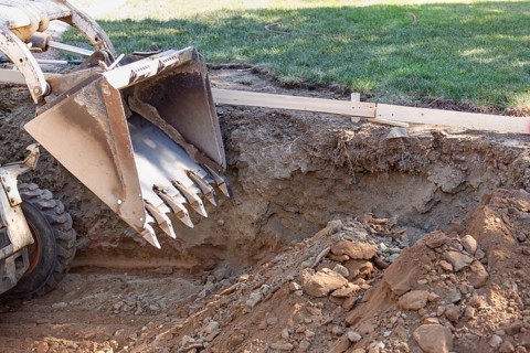 Small bulldozer digging in yard for pool installation