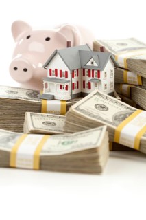 Small house and piggy bank with stacks of hundred dollar bills isolated on a white background