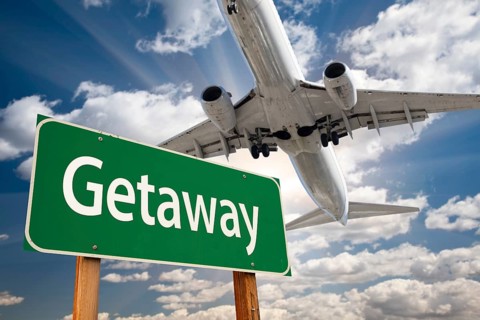 Getaway green road sign and airplane above with dramatic blue sky and clouds