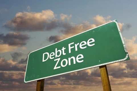 Debt free zone green road sign in front of dramatic clouds and sky