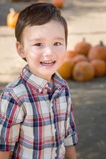 Cute mixed-race young boy having fun at the pumpkin patch