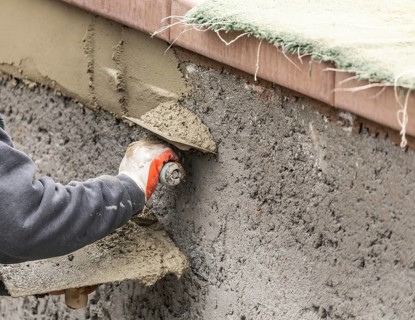 Tile worker applying cement with trowel at pool construction site