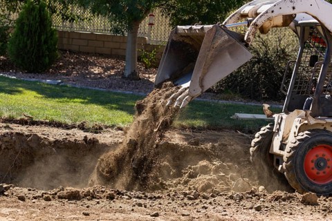 Small bulldozer digging in yard for pool installation