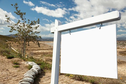 Blank real estate sign and empty construction lots