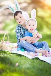 mixed-race chinese and caucasian boys outside in park playing with easter eggs