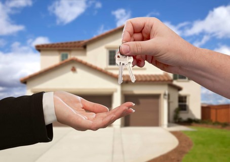 Handing over the house keys in front of a beautiful new home