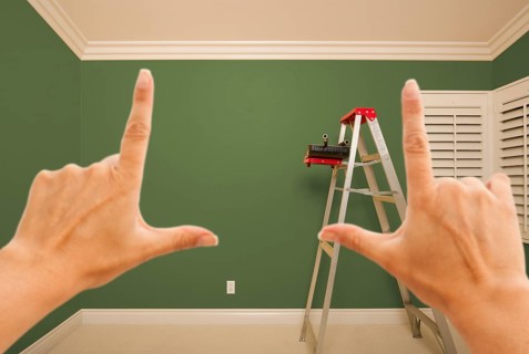 Hands framing green painted room wall interior with ladder