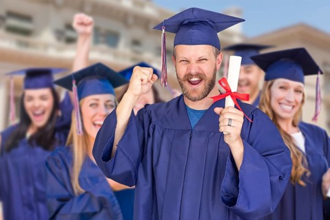 Proud male graduate in cap and gown in front of other graduates