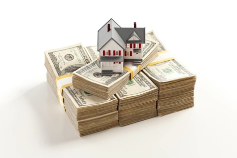 Small house on stacks of hundred dollar bills isolated on a white background