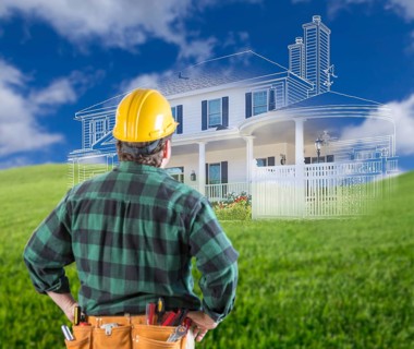 Contractor standing outdoors looking over grass site with ghosted house