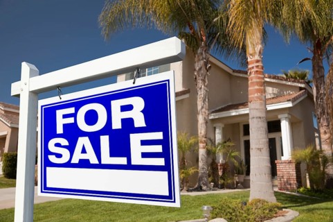 For sale real estate sign in front of house