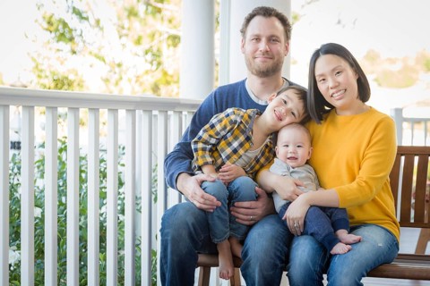 Young mixed-race chinese and caucasian family portrait on their front porch