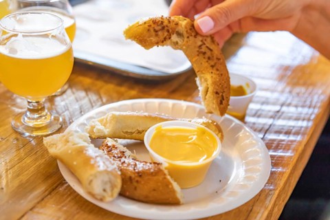 Woman enjoys warm pretzels and micro brew beer