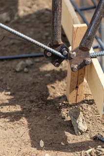 Worker using tools to bend steel rebar at construction site