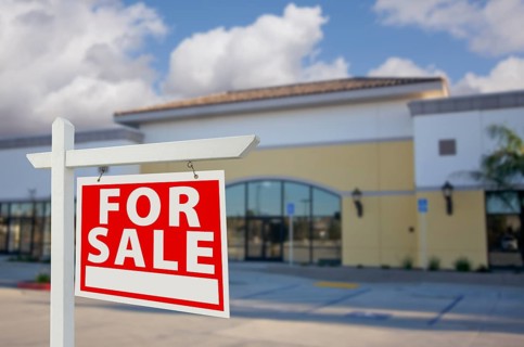 Vacant retail building with for sale real estate sign in front