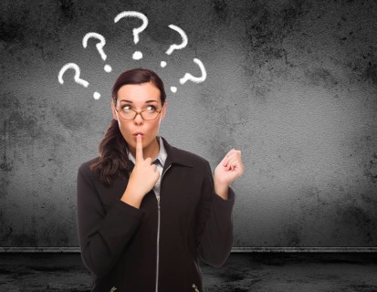 Question marks drawn above head of young adult woman in front of wall with copy space