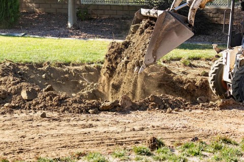 Small bulldozer digging in yard for pool installation